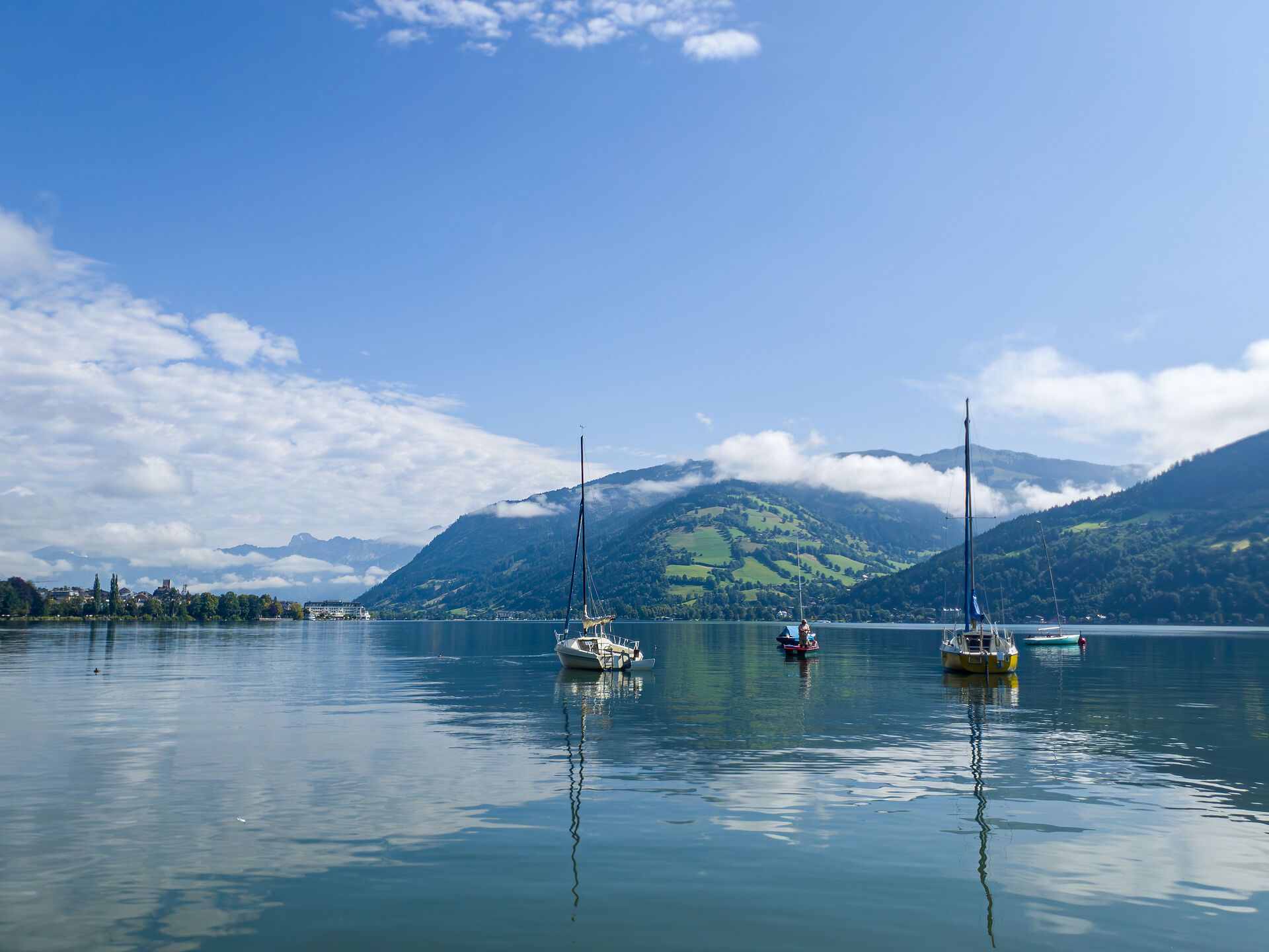 Sailing boats in lake Zell with mountains in the back